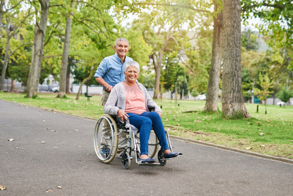 Man assisting female assisted living patient at Traditions at Brookside by pushing her wheelchair on a walking path