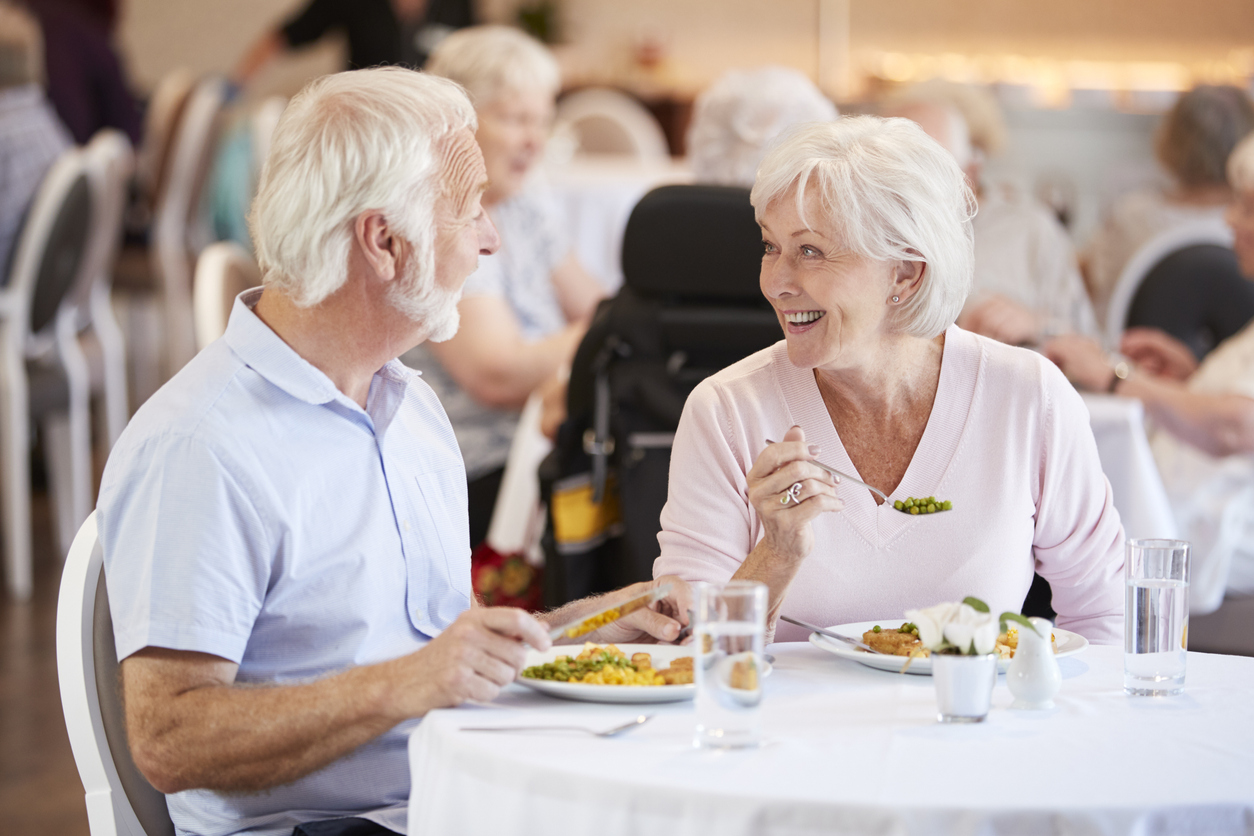 A senior couple at Traditions at Brookside in McCordsville, IN sitting together in the dining area eating dinner