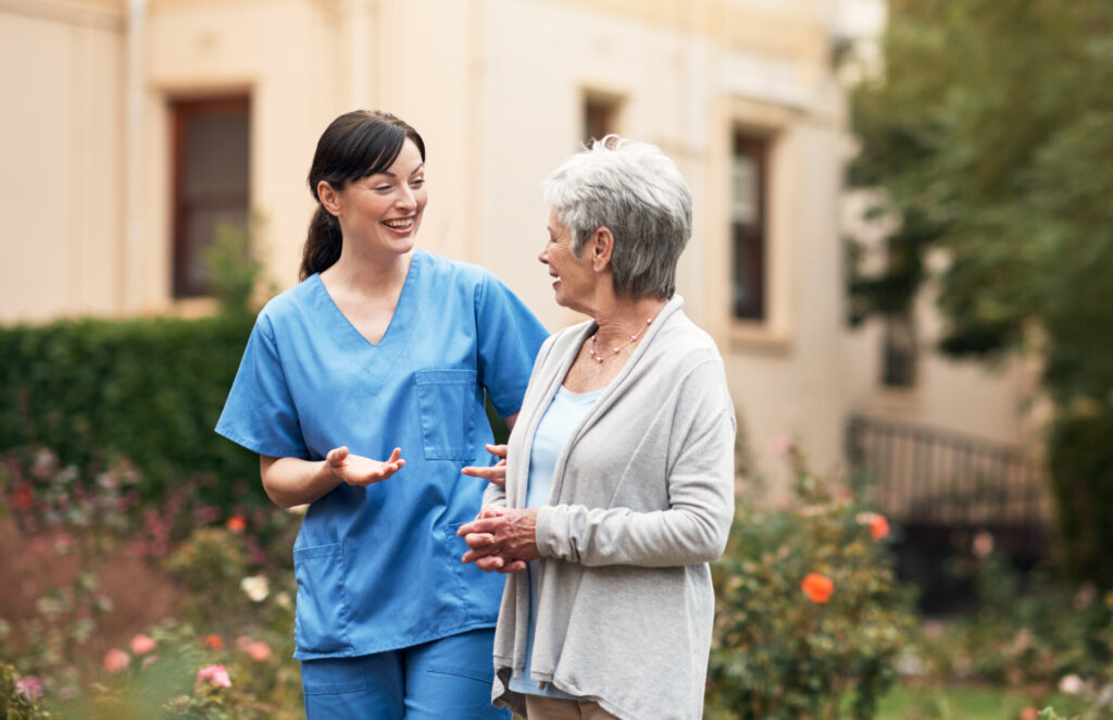 Caregiver assisting a senior living resident outdoors at Traditions at Brookside senior living community in McCordsville, IN