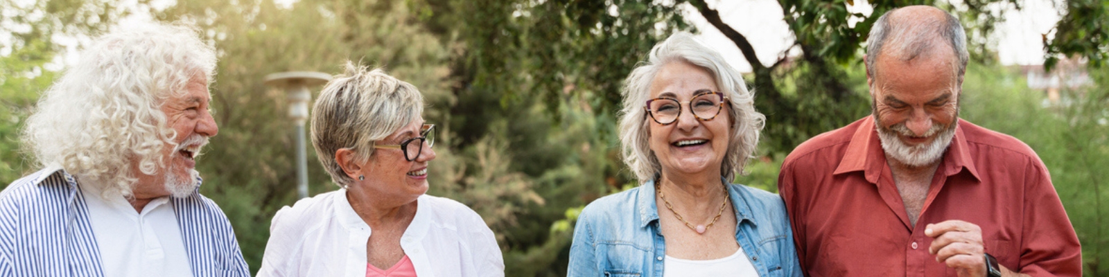 A group of 2 senior couples walking together outside and smiling.