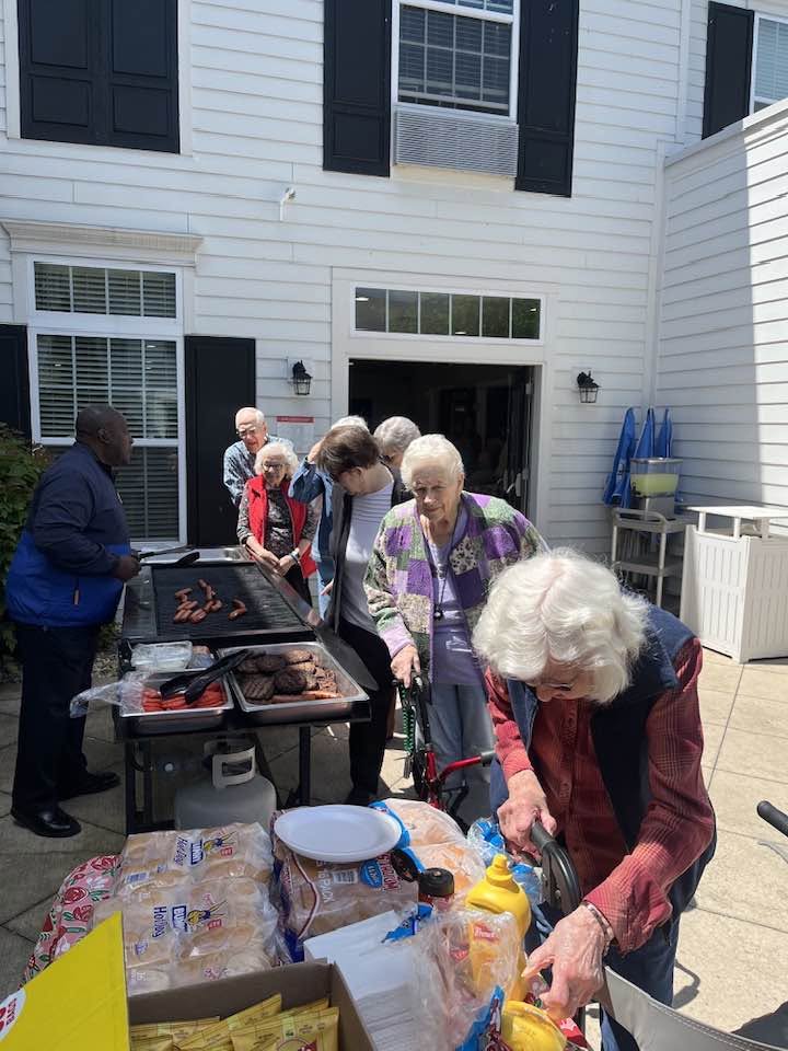 Residents enjoy hamburgers and hot dogs during an outdoor community cookout at Traditions at Brookside.