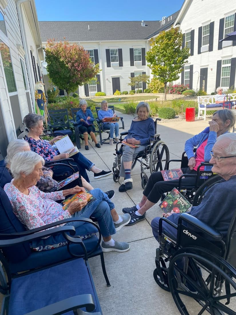 Residents gather outdoors for a book club discussion in the courtyard at Traditions at Brookside.
