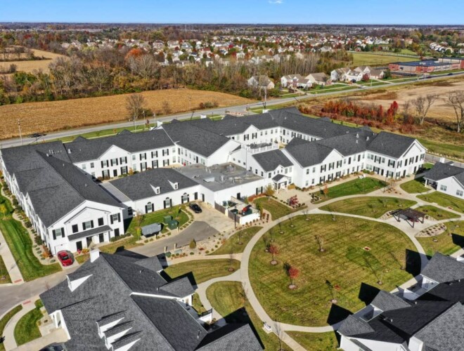 A drone shot of Traditions at Brookside senior living community showing the main campus, walking paths, and garden homes.
